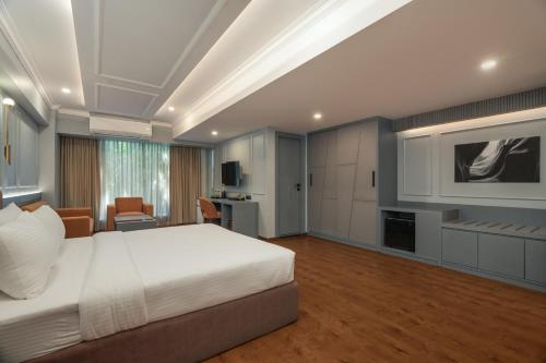 um quarto com uma cama branca e uma televisão em Pelican Inn em Bangalore