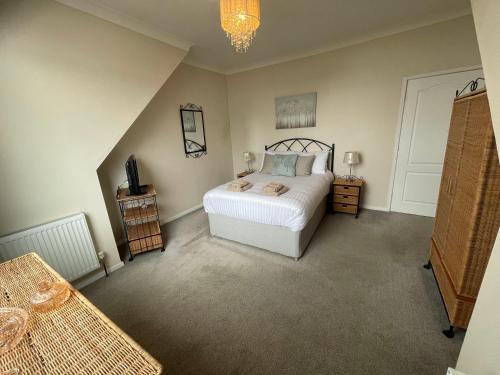 a bedroom with a white bed and a chandelier at Belle-Vue Apartments in Hunstanton