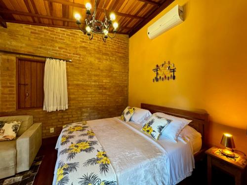 a bedroom with a bed with yellow walls and a chandelier at Pousada Chalés Jardim das Bromélias - Visconde de Mauá in Visconde De Maua