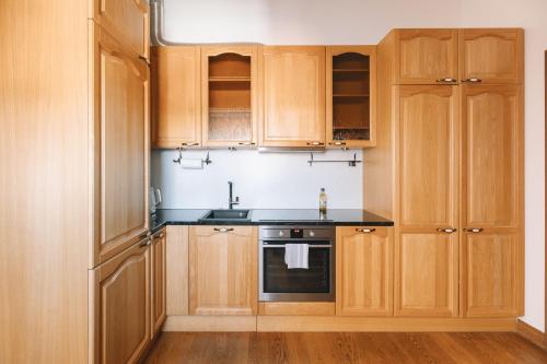 a kitchen with wooden cabinets and a sink and a stove at DICTUMFACTUM Sky Apartment in Tallinn