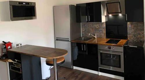 une cuisine avec des appareils en acier inoxydable et une table en bois dans l'établissement Studio de charme - coeur de ville, à Perpignan