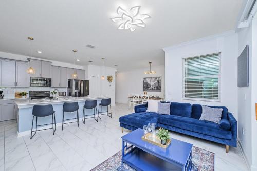a living room with a blue couch and a kitchen at Upstay - ChampionsGate Home w Private Pool & BBQ in Kissimmee