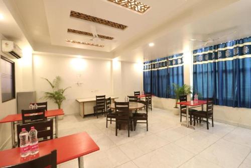 a dining room with tables and chairs and windows at Hotel Sky Wood At Airport in New Delhi