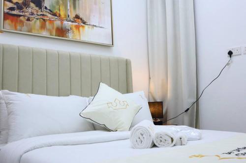 a hotel room with a bed with white sheets and pillows at MasdarCity Bliss 2BR apartment in Abu Dhabi