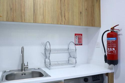 a kitchen counter with a sink and a fire extinguisher at MasdarCity Bliss 2BR apartment in Abu Dhabi