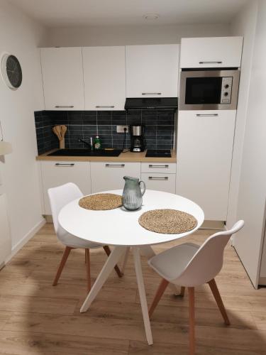 cocina blanca con mesa blanca y sillas en Studio Casa Amnéville, en Amnéville