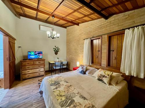 a bedroom with a bed and a dresser and a television at Pousada Chalés Jardim das Bromélias - Visconde de Mauá in Visconde De Maua