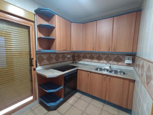 Una pequeña cocina con gabinetes de madera y un fregadero. en Apartmentos Corona, en Cazorla