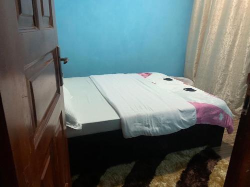 ein kleines Bett in einem blauen Zimmer mit Tagesdecke in der Unterkunft Jay Apartments in Mbarara