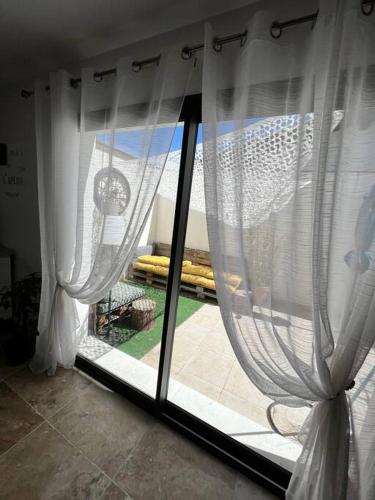 Cette chambre dispose d'une fenêtre avec des rideaux blancs. dans l'établissement Charmante maison de village, à Vauvert