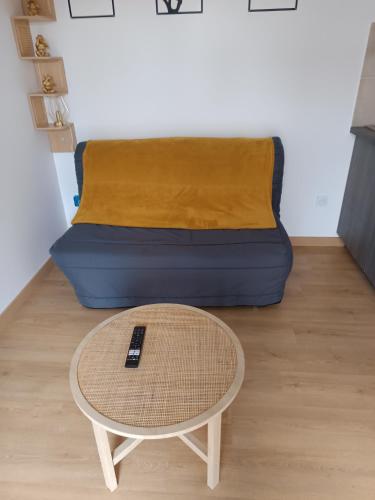ein Bett mit einem Tisch und einem Sofa in einem Zimmer in der Unterkunft Studio neuf des amandines in Pont-Sainte-Maxence