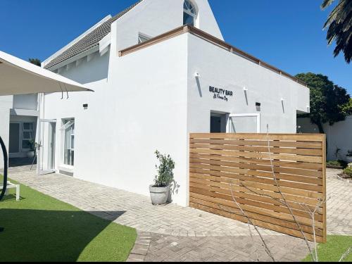 a white house with a wooden fence in front of it at Adrift Guesthouse St Francis Bay in St Francis Bay