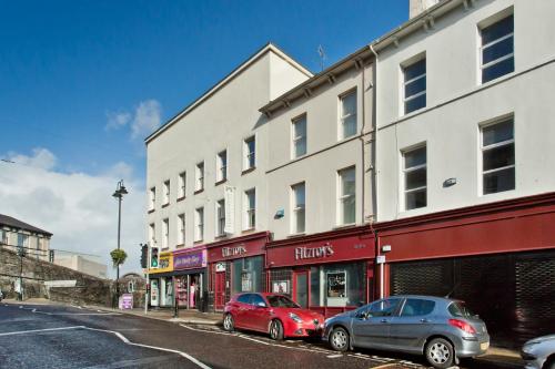two cars parked in front of a building on a street at Walled City Apartments in Derry Londonderry