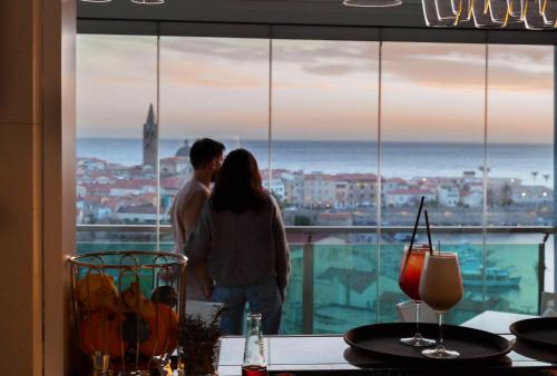 a couple looking out of a window at the ocean at Hotel Catalunya in Alghero