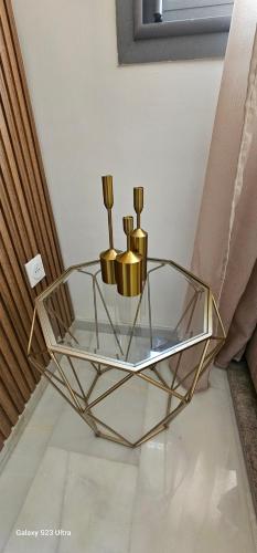 a glass table with three gold candles on it at Cosy & Confort Studio près de l'aéroport in Nouaceur