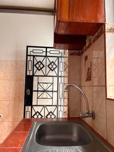a kitchen with a sink and a tile wall at ALAMEDAS APARMENTs in Pucallpa