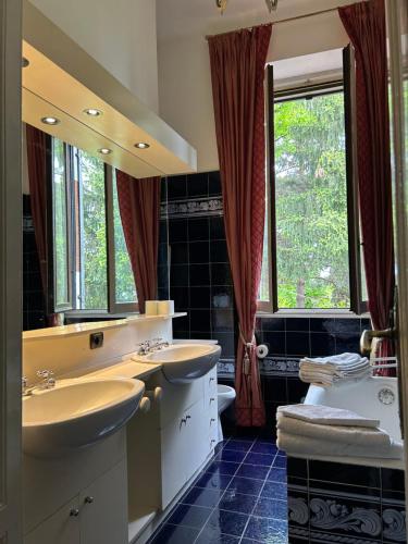un bagno con due lavandini e un grande specchio di Villa Puccini a Venegono Superiore