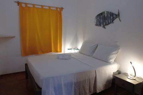 a bedroom with a white bed with a yellow curtain at Appartamento Ferreira Stella Maris Exclusive in Calheta Do Maio