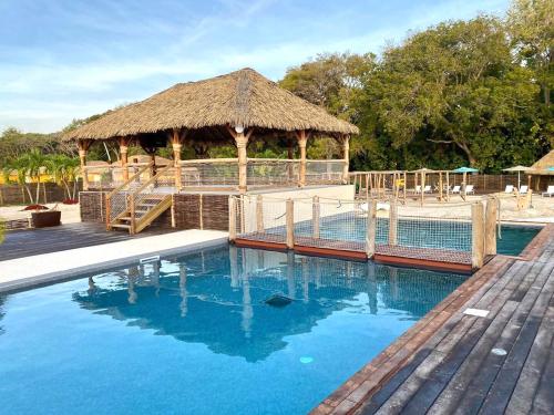a swimming pool with a gazebo and blue water at Bungalow La Kawannaise - Piscine, Terrasse, Plage in Grand-Bourg