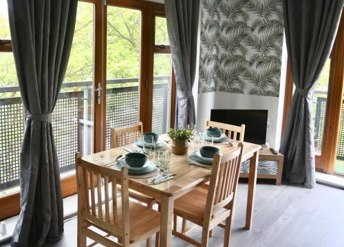 een houten eettafel met 4 stoelen en een tafel met een stoel bij Modern Spacious Apartment in Thornton Heath