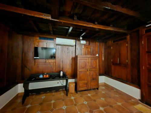 een keuken met houten wanden, een televisie en een kast bij Gypsea Marari in Alleppey