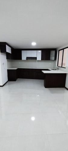 an empty room with a white floor and a kitchen at CASA EN CONDOMINIO J2 3 DORMITORIOS in Cuenca