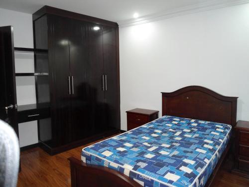 a bedroom with a bed and a black cabinet at CASA EN CONDOMINIO J2 3 DORMITORIOS in Cuenca