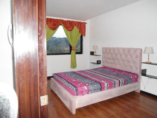 a bedroom with a bed and a window at CASA EN CONDOMINIO J2 3 DORMITORIOS in Cuenca