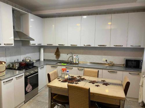 eine Küche mit weißen Schränken und einem Tisch mit Stühlen in der Unterkunft Apart Hotel ZUKA in Kobuleti