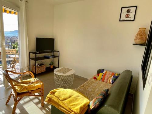 sala de estar con sofá verde y TV en Appartement cosy vue mer à 50 m de la plage - refait à neuf et climatisé, en Le Pradet
