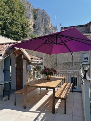 un parapluie violet au-dessus d'une table de pique-nique sur une terrasse dans l'établissement Maison Bossanne, à Barbières