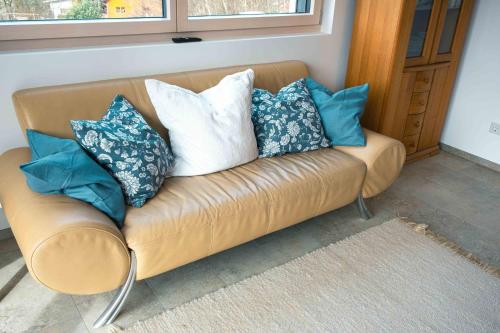 a brown couch with blue and white pillows on it at Ferienwohnung Weitblick in Bruchweiler-Bärenbach