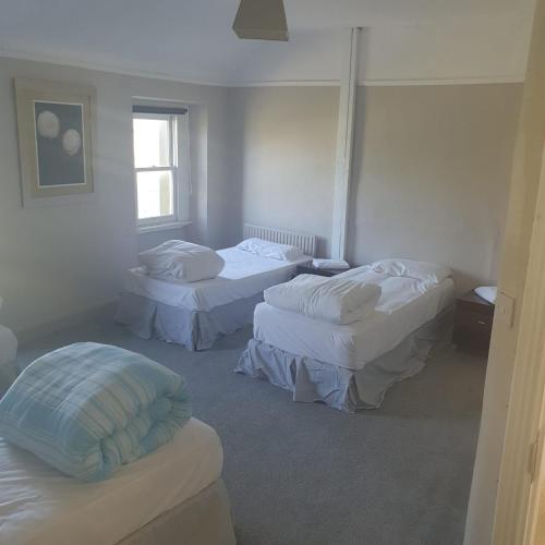 um quarto de hotel com três camas e uma janela em John Street Guest House em Kilkenny
