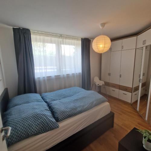 a bedroom with a bed with blue sheets and a window at Höher Auszeit- Bergisch schön in Wiehl