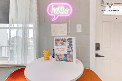 a white table with a neon sign on a wall at The Moose #10 - Stylish Loft with King Bed, Free Parking & Wi-Fi in Memphis