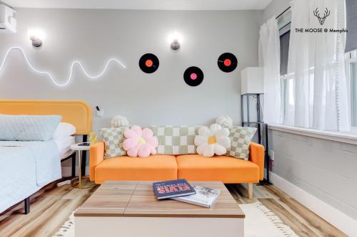 a living room with an orange couch and records on the wall at The Moose #10 - Stylish Loft with King Bed, Free Parking & Wi-Fi in Memphis