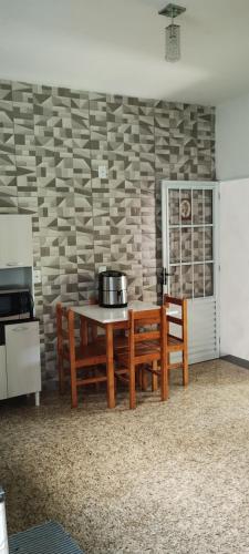 una cocina con mesa, 2 bancos y una pared en Kit net montanha mágica, en São Thomé das Letras