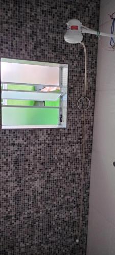 baño con espejo y una luz en la pared en Kit net montanha mágica en São Tomé das Letras