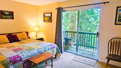 Lake AlmanorにあるCedar Ridge Retreat Lake Almanorのベッドルーム1室(ベッド1台付)、バルコニー(ガラスのスライドドア付)