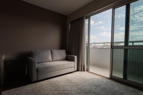 ein Wohnzimmer mit einem Sofa und einem großen Fenster in der Unterkunft eSuites Belo Horizonte Minascasa in Belo Horizonte