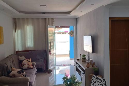 a living room with a couch and a sliding glass door at Casa em Unamar com piscina privativa in Cabo Frio