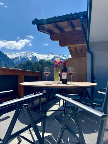 una mesa con 2 copas de vino y flores en el balcón en Apartment Waldherz, en Wald im Pinzgau