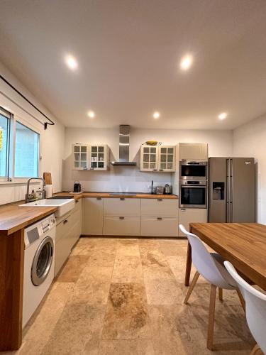 une cuisine avec des armoires blanches et une table en bois dans l'établissement Maison : L'Appart des Anges 10 personnes, à Althen-des-Paluds