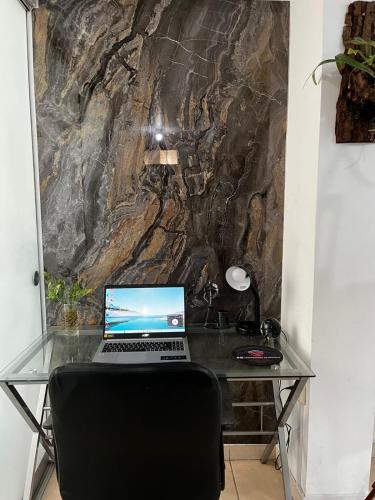 a glass desk with a laptop computer on it at Sumaq AirPort in Lima