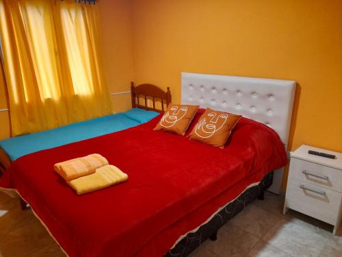 1 dormitorio con 1 cama roja y 2 almohadas en Departamento franco 3 en Los Antiguos