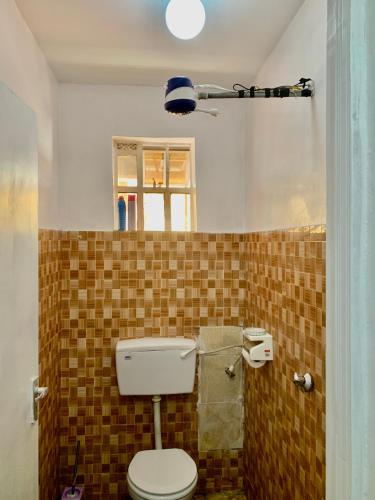 a bathroom with a toilet in a tiled wall at Cozystay in Nakuru