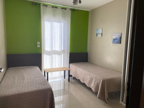 une chambre avec deux lits et une fenêtre avec des murs verts dans l'établissement ARGELES sur MER APPT ETAGE CALELLA TOUT CONFORT JARDIN PISCINE PARKING WIFI, à Argelès-sur-Mer