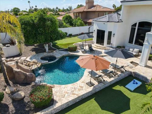 a backyard with a swimming pool with an umbrella at Two Separate Game Rooms, Heated Pool, Spa, B-ball Court in Mesa