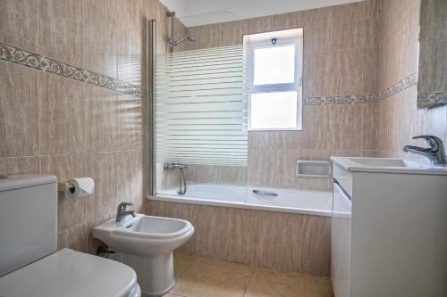 La salle de bains est pourvue de toilettes, d'une baignoire et d'un lavabo. dans l'établissement Oasis park 2 bedroom top floor Apartment AT72, à Portimão