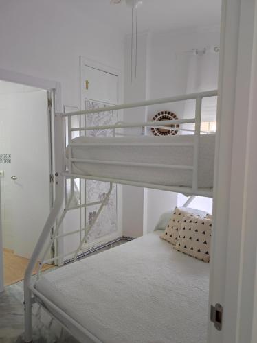 um beliche num pequeno quarto com uma escada em Apartamentos home Chipiona em Chipiona
